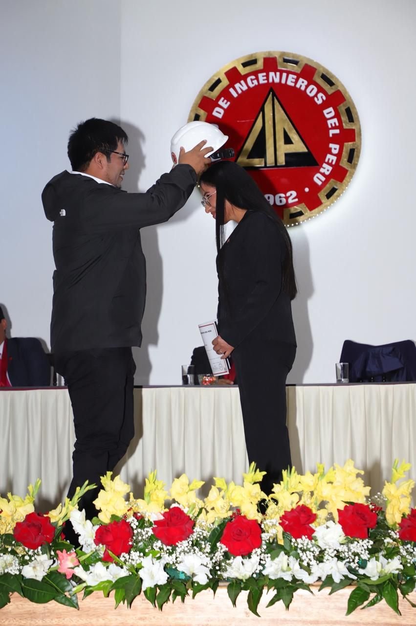 El director del estudio coloca el casco a la jefa de formulación y evaluación de proyectos durante su colegiatura en el Colegio de Ingenieros del Perú.